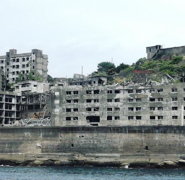 Battleship Island - dilapidated concrete buildings and a tall sea wall that surrounds the entire island.