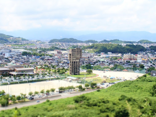 Abandoned places in Japan - Shime Winding Tower standing out from the nearby colourful housing and lush greenery