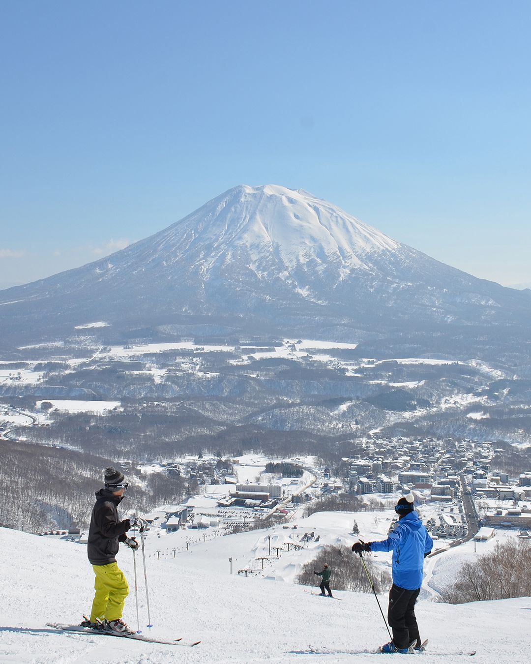 Cities in Japan to see snow - people equipped with ski gear admiring the mountain view at a skiing course in Niseko