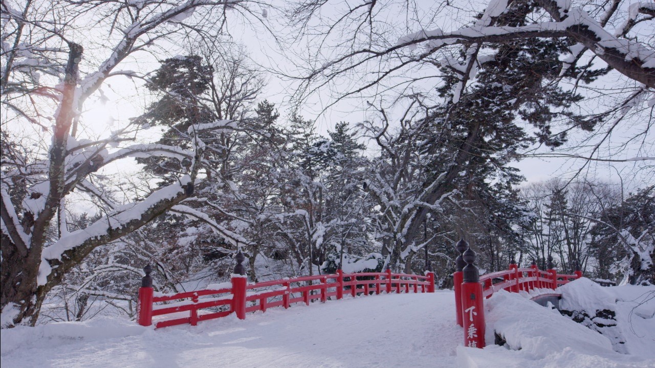 Cities in Japan to see snow - red bridge at Hirosaki Park